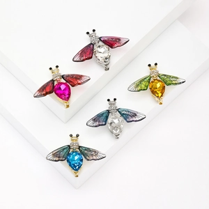 Five colorful crystal honey bee brooches with sparkling diamonds on geometric stands