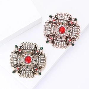 Baroque style round brooches with red gemstones and crystals on white geometric stand