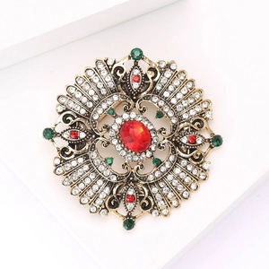 Detailed view of Baroque round brooch with red crystal center and green rhinestones