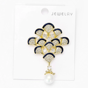 Détail macro d'une broche en éventail avec émail bleu, zircons et une perle pendante
