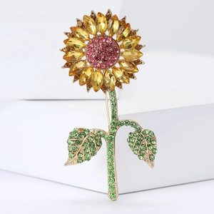 Exquisite gold alloy sunflower brooch with yellow rhinestones and green leaves on a white stand