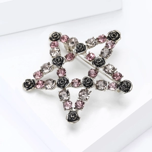 Detailed close-up of a star-shaped brooch with black roses and colorful crystals