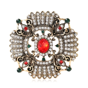 Vintage Baroque gold brooch with red oval stone and multicolor rhinestones on white background