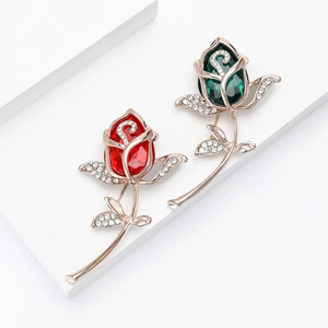 Elegante Rosenbrosche mit Strasssteinen in Rot und Grün auf goldfarbenem Metall