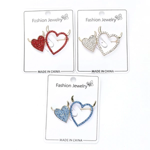 Detail view of heart-shaped devil pins in red, white and blue with rhinestone inlay