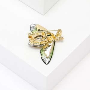 Detailed back view of a crystal bee brooch in gold alloy on a white geometric stand