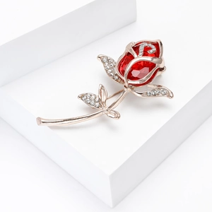 Detail der Roségold-Blumenbrosche mit rotem Edelstein und weißen Strasssteinen auf Block