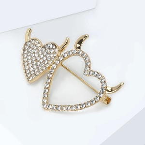 Detailed macro view of golden double heart devil pin with sparkling clear rhinestones