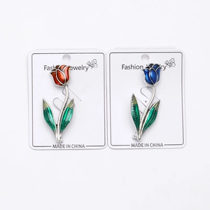 Détail de broches tulipes rouges et bleues avec feuilles émaillées sur carton