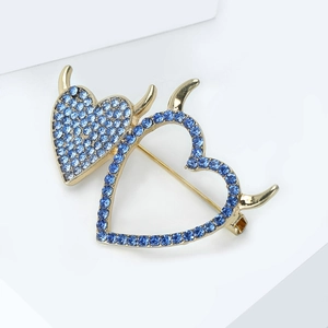 Detailed view of dual heart devil horn brooch featuring sparkling blue rhinestones