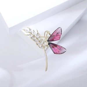 Detailaufnahme einer goldenen Libellen-Brosche mit rosa Flügeln und Kristallbesatz
