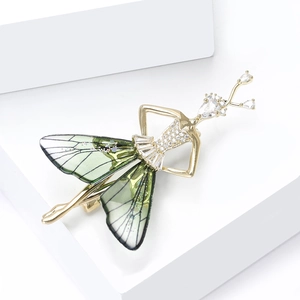 Detaillierte Nahaufnahme einer Gold-Ballerina-Brosche mit grünen Flügeln und Kristallen