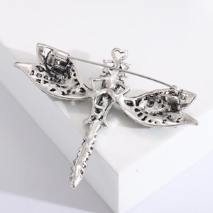 Macro detail of retro dragonfly brooch back showing hollow wing textures and secure pin