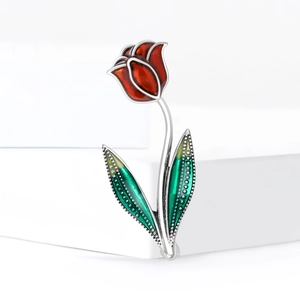 Broche tulipe rouge élégante avec feuilles vertes et tige argentée sur socle blanc