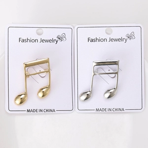 Detailed macro view of musical note brooches in polished gold and silver metal finishes