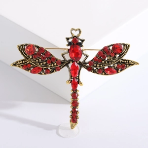 Vintage gold dragonfly brooch with deep red rhinestones on a minimalist white stand