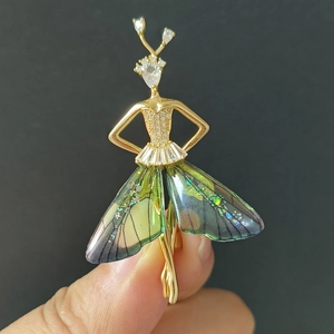 Makro-Detail einer goldenen Ballerina-Brosche mit Zirkonia-Steinen und bunten Flügeln