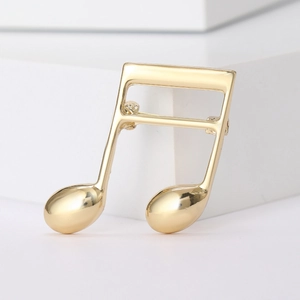Detailed view of a polished gold music note brooch on a white geometric block
