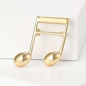 Macro view of a gold musical note brooch with a polished mirror finish on white background