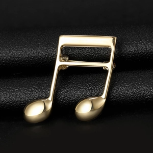Macro shot of musical note brooch with polished gold finish on black leather backdrop