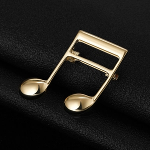 Macro shot of musical note brooch with polished gold plating on black leather texture