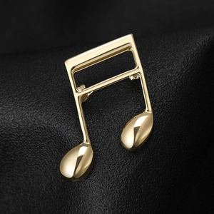 Macro shot of minimalist gold music note brooch on a premium black leather background