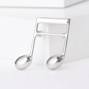 Detailed view of musical note brooch with silver polished finish on a minimalist background
