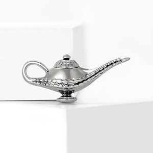 Polished silver Aladdin lamp brooch with detailed relief on white geometric stands