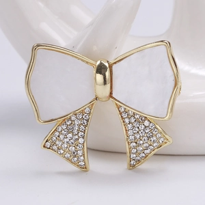 Macro shot of gold bow brooch with mother of pearl finish and sparkling rhinestones