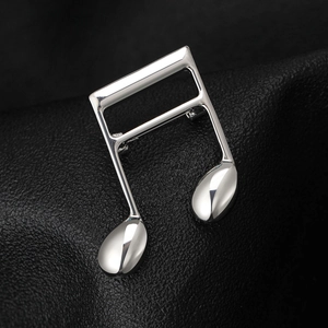 Detailed close-up of a silver polished musical note brooch on black leather background