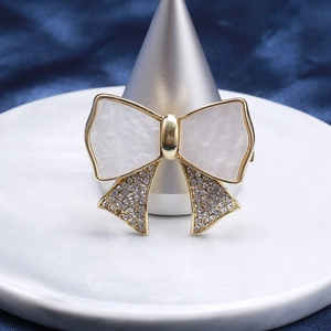 Close-up of bow brooch with white mother-of-pearl and crystal pavé on marble