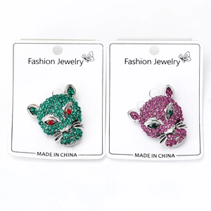 Detailed close-up of handmade leopard head brooches with green and purple rhinestones