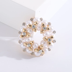 Detail van parelkrans broche met gouden legering bloemen en glinsterende strassteentjes