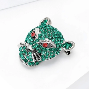 Macro detail of leopard head brooch featuring green crystals and vibrant red gem eyes