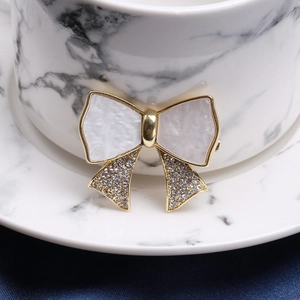 Detail of elegant bow brooch with gold trim and crystal inlay on marble surface