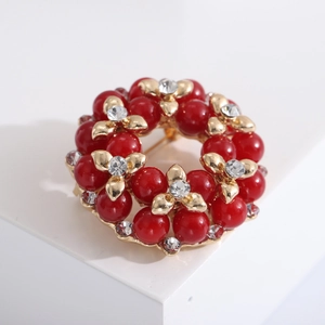 Elegante bloemenkrans broche met rode parels en fonkelende kristallen in goudkleur