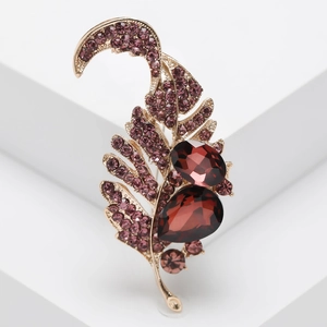 Detailed macro view of vintage gold leaf brooch with purple crystals and red gems