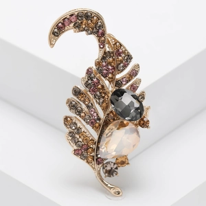 Detailed macro of vintage alloy feather brooch with purple rhinestones and smoke grey gem