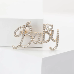 Broche lettre Baby en alliage doré ornée de strass brillants et d'un détail en cœur