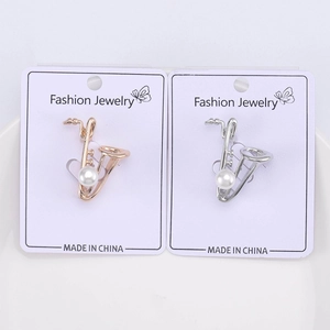 Gros plan de broches saxophone en or rose et argent avec perles sur carte de bijoux