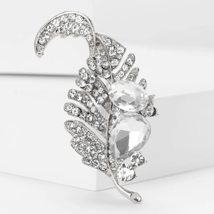 Detailed shot of silver feather brooch with rhinestones and pear-shaped gemstones