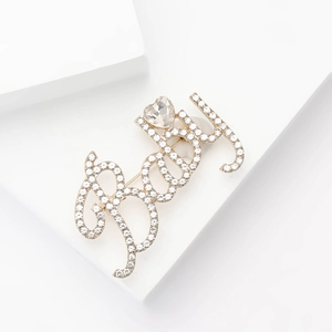 Détail macro d'une broche Baby dorée avec strass scintillants et pierre en forme de cœur
