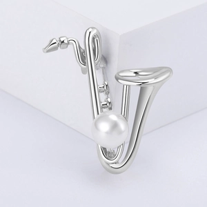 Détail de la broche saxophone argentée avec métal poli et une perle blanche centrale