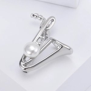 Détail de la broche saxophone argentée avec perle blanche sur fond minimaliste