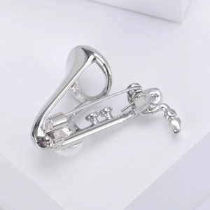 Vue macro de la broche saxophone argentée montrant l'épingle de fixation et la perle