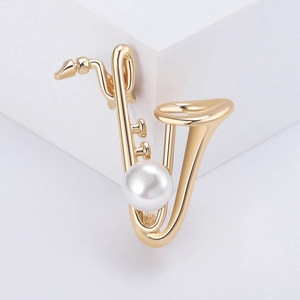 Élégante broche saxophone dorée avec perle blanche sur un fond blanc minimaliste
