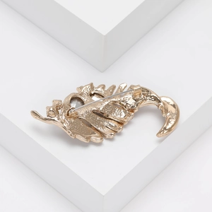 Detailed back view of golden leaf brooch showing safety pin clasp and textured metal finish