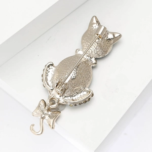 Detailed back view of light gold cat brooch with bow charm and safety pin closure