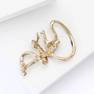 Macro shot of abstract golden gymnast brooch showing fine polished alloy finish and pin