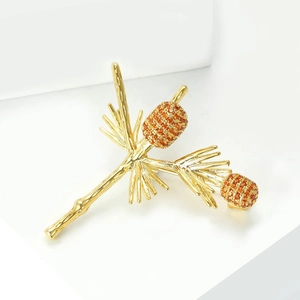 Elegant pine branch brooch in gold plating with orange zircon crystals on white stand